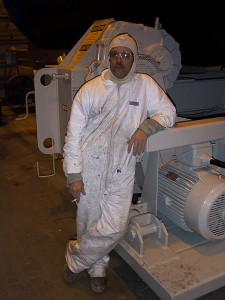 Dave in full paint suit leaning against machinery